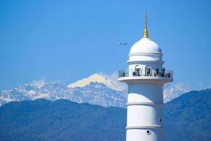 a white lighthouse with mountains in the background at himalayan hotel in Jogīkuti