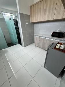 a kitchen with a white tiled floor and cabinets at Exclusive Changlun Room in Bukit Kayu Hitam +13 photos