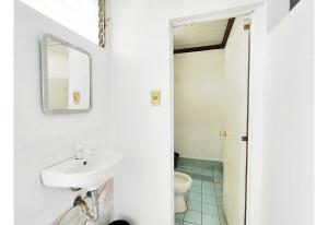 a white bathroom with a sink and a toilet at OYO 1214 Cherry Travellers Inn in San Jose de Buenavista