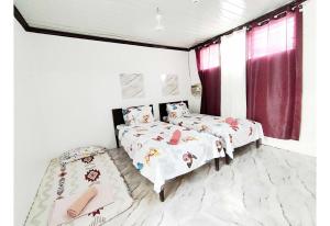 two twin beds in a room with red curtains at OYO 1214 Cherry Travellers Inn in San Jose de Buenavista