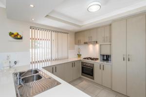 a kitchen with white cabinets and a sink at Serenity Townhouse in Mandurah