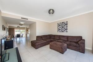 a living room with a brown couch and a table at Serenity Townhouse in Mandurah