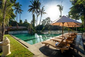 a group of chairs with an umbrella and a swimming pool at Sarva Ubud Villas & Spa in Ubud