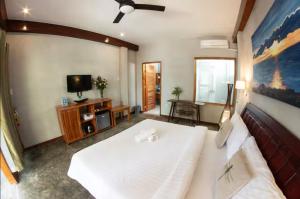 a bedroom with a large white bed and a tv at Republika Beach Resort in San Juan