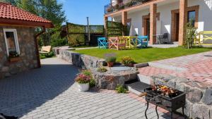 a garden with a stone wall and a patio at Edelweiss Vila Šventoji in Šventoji