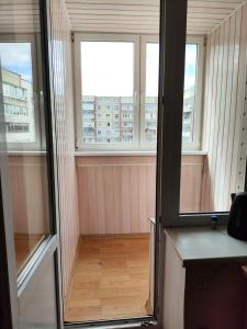 a room with three windows and a wooden floor at Visaginas Taikos 84 in Visaginas