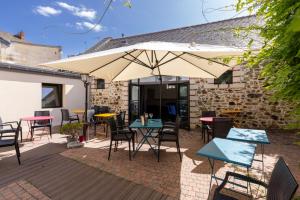 a patio with tables and chairs and an umbrella at Auberge de la Loire in Montjean-sur-Loire
