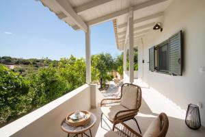 a patio with chairs and a table on a balcony at Leonti Maison in Egina