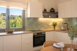 a kitchen with white cabinets and a table and a window at Leonti Maison in Egina +11 photos