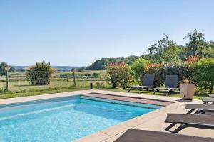 a swimming pool with two chairs and a table at Aux Charmes D'antan - Chambre in Sevremont