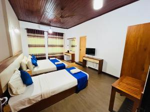 a hotel room with two beds and a television at Hotel Elephant Bay - World's Best Place to See the Elephants in Pinnawala
