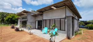 a house with two blue chairs in front of it at Rumah Cermin in Langkawi Intl