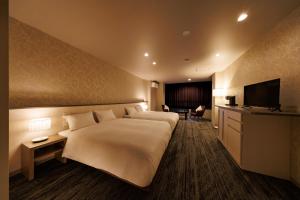 a hotel room with two beds and a television at ホテルグランリゾート蓼科 in Chino