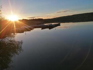 una barca su un lago con il sole che si riflette sull'acqua di Ferienwohnung Eifelglück a Utzerath