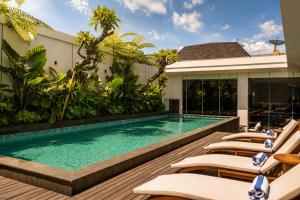 a swimming pool with lounge chairs next to a house at Arkadewi Boutique Hotel Prawirotaman in Yogyakarta