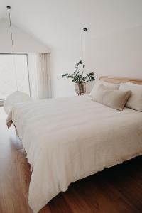 a bedroom with a large white bed with a potted plant at View Street Studios - Yarri in Albany