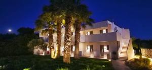 a large white building with palm trees in front of it at Anemone Premium Suites Faliraki in Faliraki