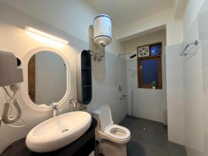 a bathroom with a sink and a toilet and a mirror at Oak & Amber Retreat in Manāli +18 photos