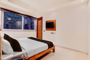a bedroom with a bed and a television in it at Townhouse Oak Sector 31 Noida in Noida +23 photos