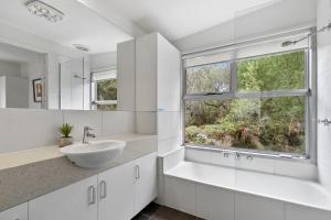a white bathroom with a sink and a window at Timbara Hideaway - Ocean Views - Pet Friendly in Moggs Creek