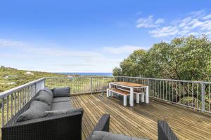 a patio with a couch and a table on a deck at Timbara Hideaway - Ocean Views - Pet Friendly in Moggs Creek