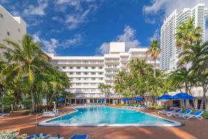 a large hotel with a swimming pool and palm trees at Radisson Resort Miami Beach in Miami Beach