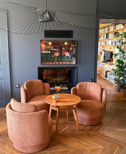 a living room with two chairs and a table and a fireplace at Hôtel Particulier Nontron - chambre d'hôtes et meublés de tourisme in Nontron