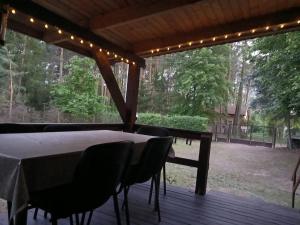 a table and chairs on a deck with lights at Domek nad Narwią in Zatory