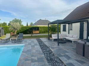 a patio with a couch and an umbrella next to a pool at La Villa cocooning in Changé