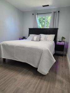 a bedroom with a large bed with white sheets and a window at Cozy SeaTac home in SeaTac
