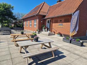 two wooden picnic tables in front of a building at Stædets lejlighed in Bøvlingbjerg