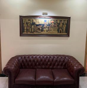 a brown leather couch sitting under a painting on a wall at Rahat Hotel in Ganja
