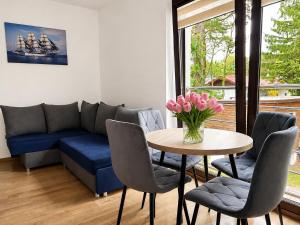 a living room with a blue couch and a table with pink flowers at Willa Magda in Jastrzębia Góra