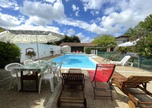 a patio with a table and chairs and a pool at Baserian in Saint-Pé-de-Léren