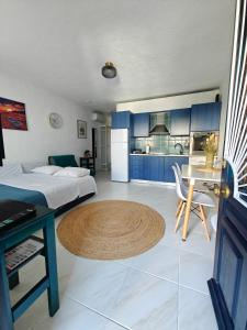 a bedroom with a bed and a kitchen with blue cabinets at Brilliance Sea View Apartments in Ouranoupoli