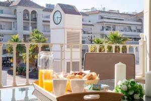 a tray of breakfast food on a balcony with a clock tower at Plaza España - Nerja centro in Nerja