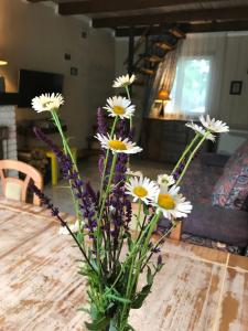a vase filled with white and purple flowers on a table at Villa del Grossa Будинок з каміном та чаном на дровах in Kuchakiv