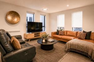 a living room with leather furniture and a flat screen tv at Cathedral Junction Apartments in Christchurch