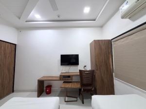 a room with a desk with a tv and a chair at Hotel SR Executive, Akola in Akola