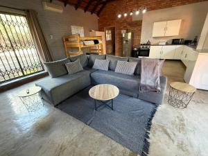 a living room with a couch and tables and a kitchen at Bush and Gables in Marloth Park