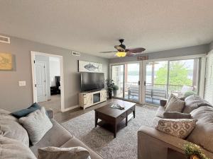 a living room with a couch and a tv at Lakefront Vibes Waterfront Pool in Osage Beach +26 photos