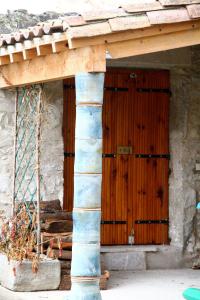 een houten deur in een stenen gebouw met een veranda bij Chambre d'Hôtes la Poterie in Caunes-Minervois