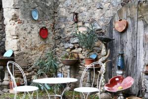 een stenen muur met tafels en stoelen voor een muur bij Chambre d'Hôtes la Poterie in Caunes-Minervois