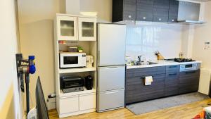 a kitchen with a refrigerator and a microwave at Nagoya Minpaku, KANAYAMA BASE in Mutsunochō
