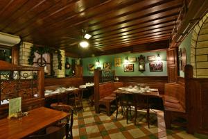 a restaurant with wooden tables and chairs and green walls at Hunyadi in Győr