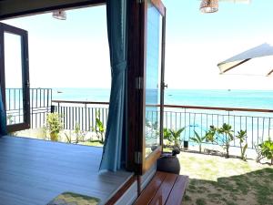a room with a balcony with a view of the ocean at Hidden Beach Bungalow Sea View in Hoi An
