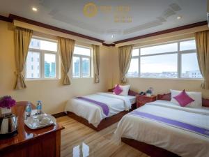 a hotel room with two beds and windows at The Mou Hotel in Phnom Penh