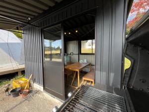 a black house with a grill and a table at 里山グランピングむすび in Mizunami
