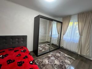 a bedroom with a red bed and a mirror at Apartamente Giu in Giurgiu +3 photos