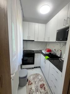 a small kitchen with white cabinets and a sink at Apartamente Giu in Giurgiu